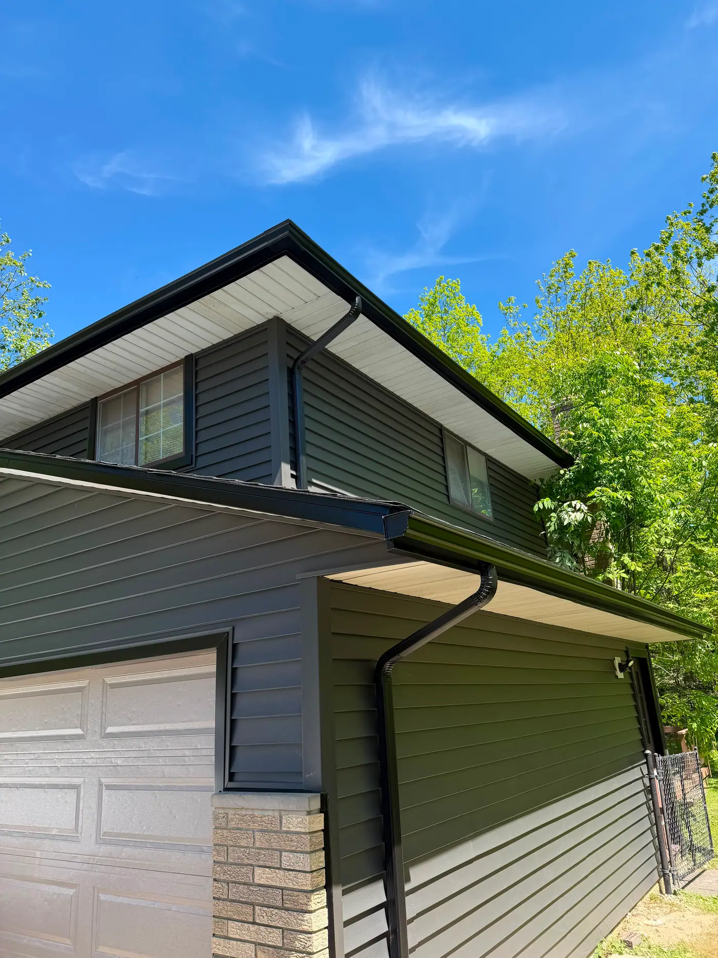Two-tone charcoal and olive-green siding with crisp black gutters and downspouts on a Greater Cleveland home.